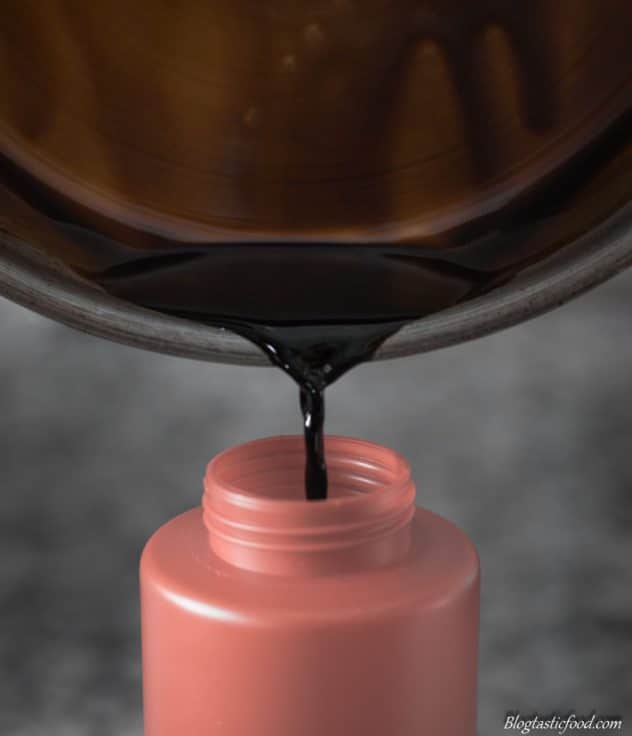 Balsamic glaze being transferred from a pan to a squeeze bottle.