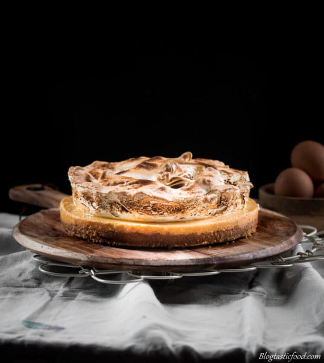 An eye level photo of a gluten free lemon meringue pie with a bowl of eggs in the background. 