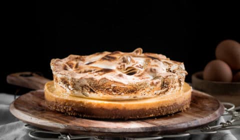 A gluten free lemon meringue pie served on a round wooen board.