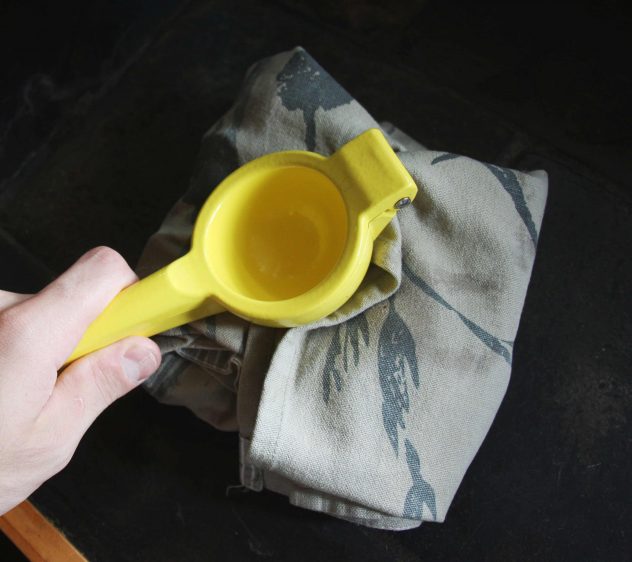 Someone using a lemon squeezer to bash ice wrapped in a tea-towel. 