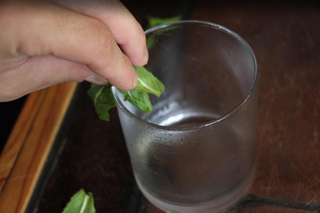 Fresh mint being rubbed around the rim of a chilled glass. 