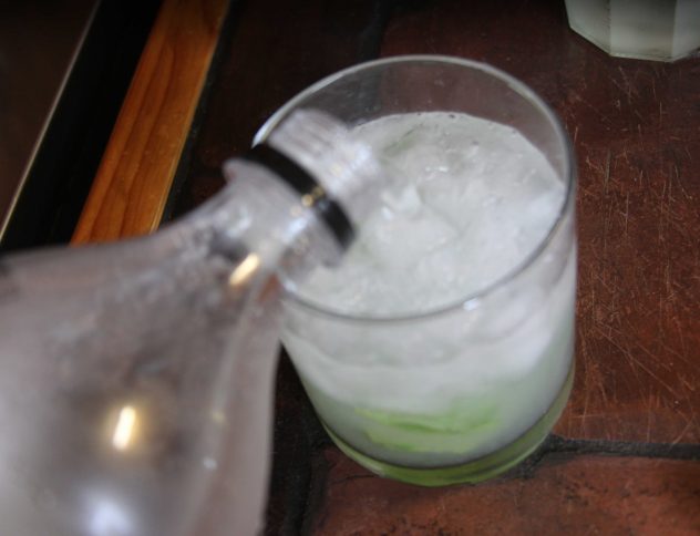 A mojito being topped up with soda water. 
