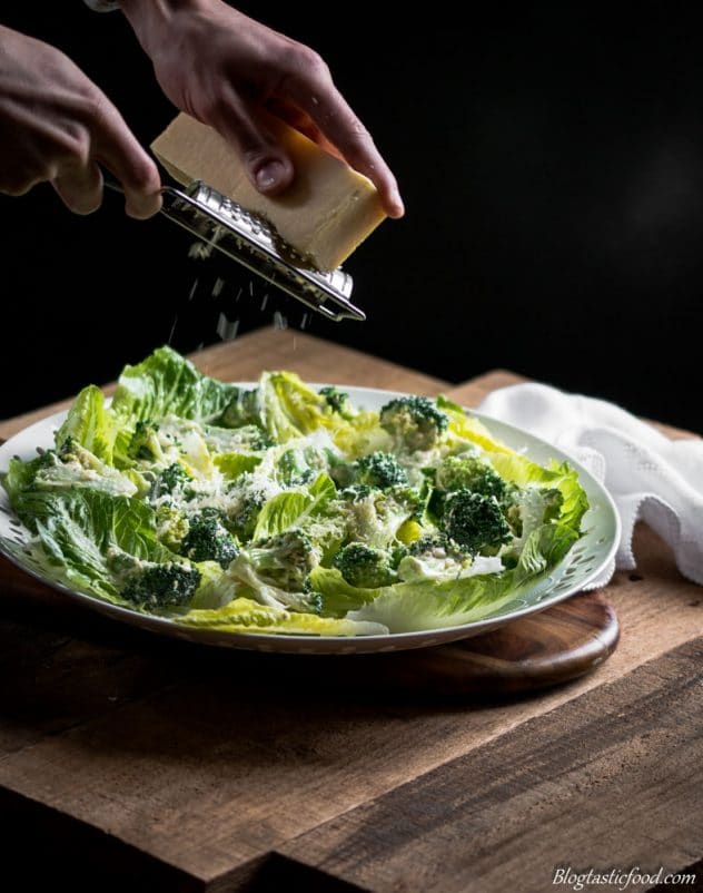 Parmesan Cheese being grated over blanched broccoli and baby cos lettuce.