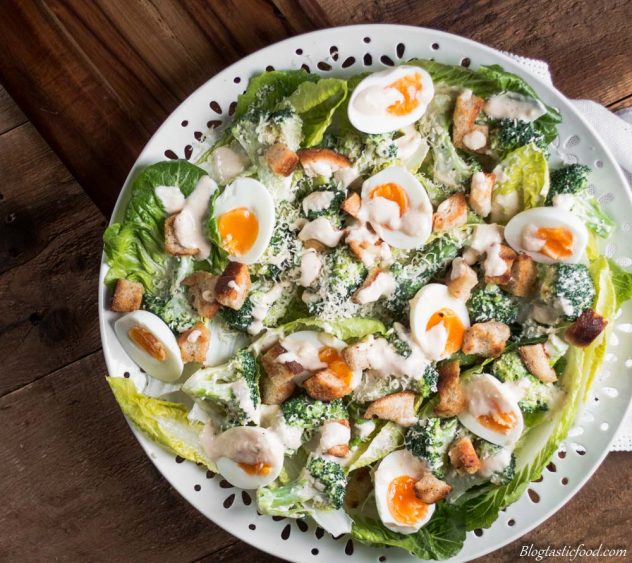 An overhead shot of broccoli Caesar salad on a white platter.