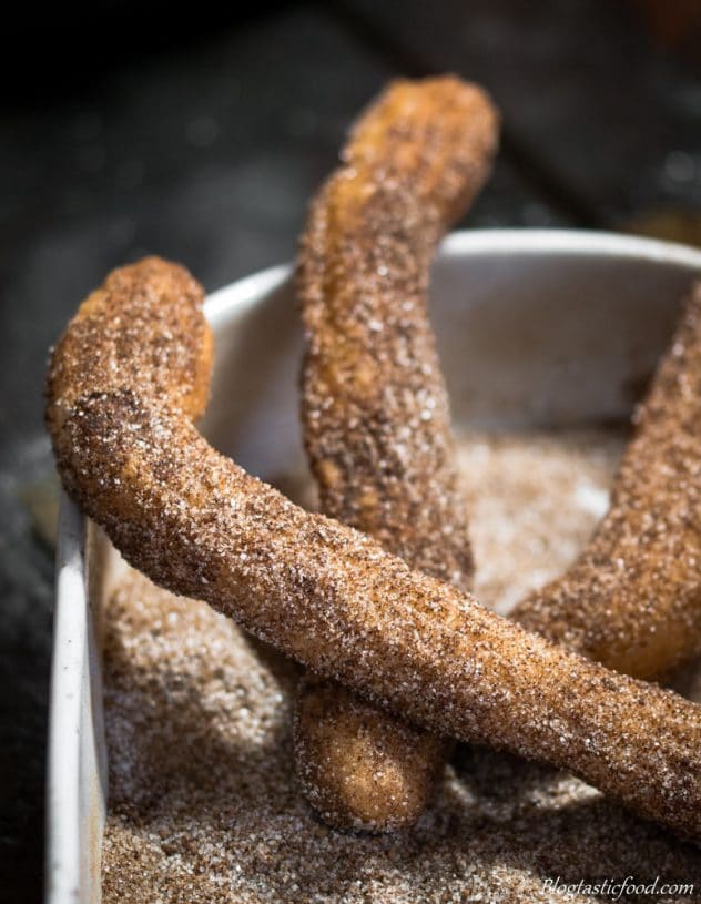 A close up of a well dusted churro.