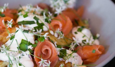 A photo of crispy potato cakes topped with sour cream and chives and smoked salmon.