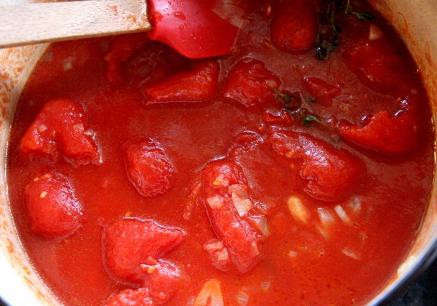 Tomato sauce being stirred in a pot.