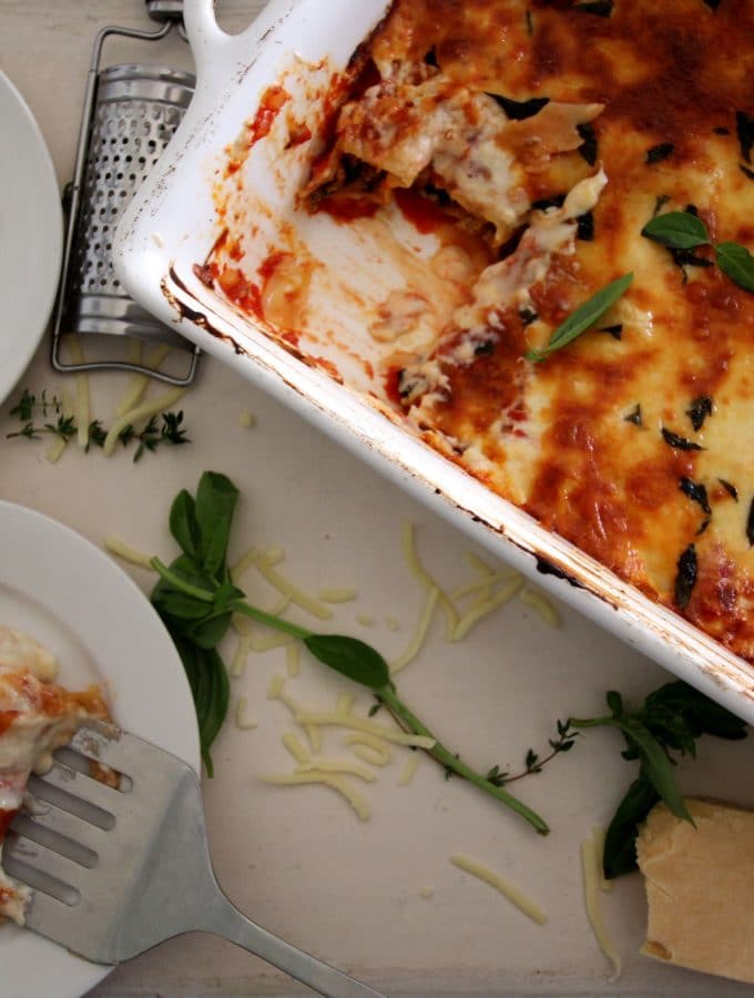 A overhead photo of cannelloni in a baking tray being served on a plate.