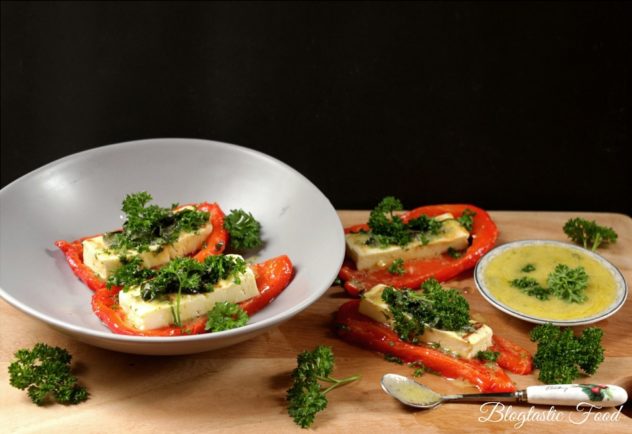 Grilled halloumi cheese served with roasted red peppers serve on a board and a plate. 