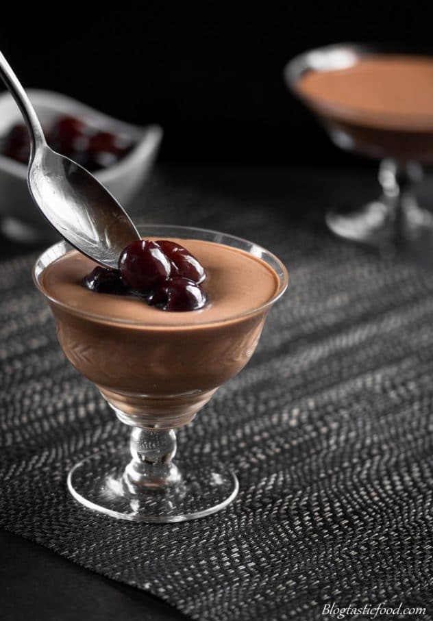 Someone spooning booze soaked cherries over mint chocolate mousse.