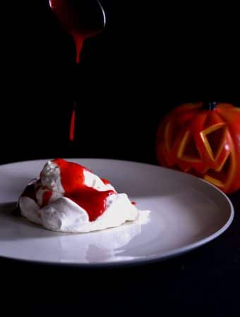 A photo of strawberry coulis being dripped on a meringue to resemble blood for Halloween.