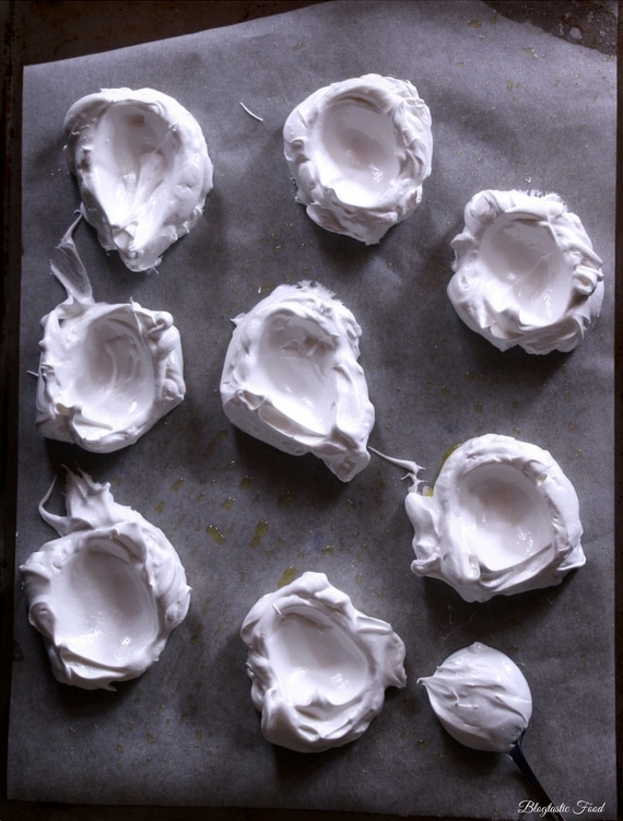 An overhead photo of mini raw pavlovas on a baking tray ready to go in the oven.