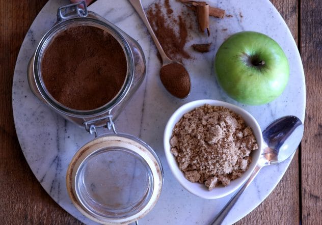 An overhead photo of cinnamon, brown sugar and an apple. 