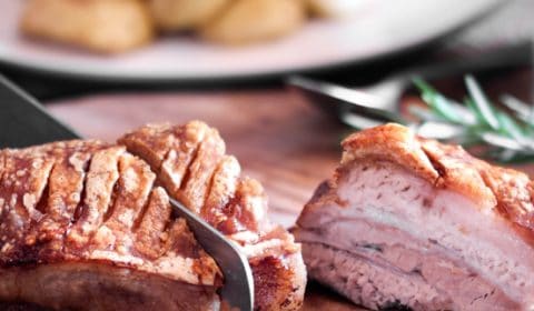 Roasted pork belly with crispy crackling getting sliced.