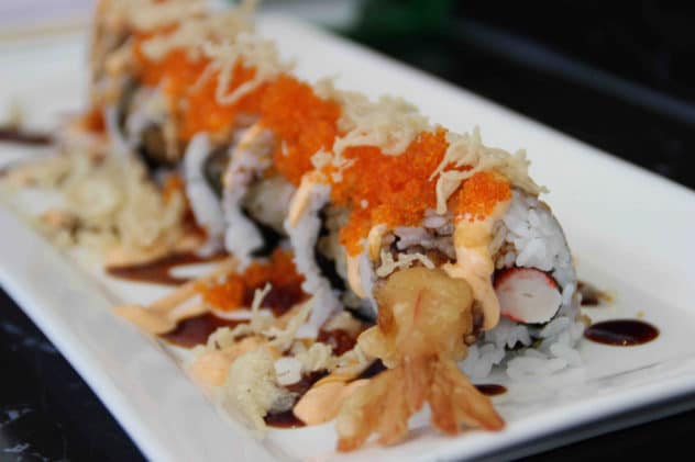 A platter of tempura prawn filled sushi rolled topped with caviar and spicy mayonnaise.