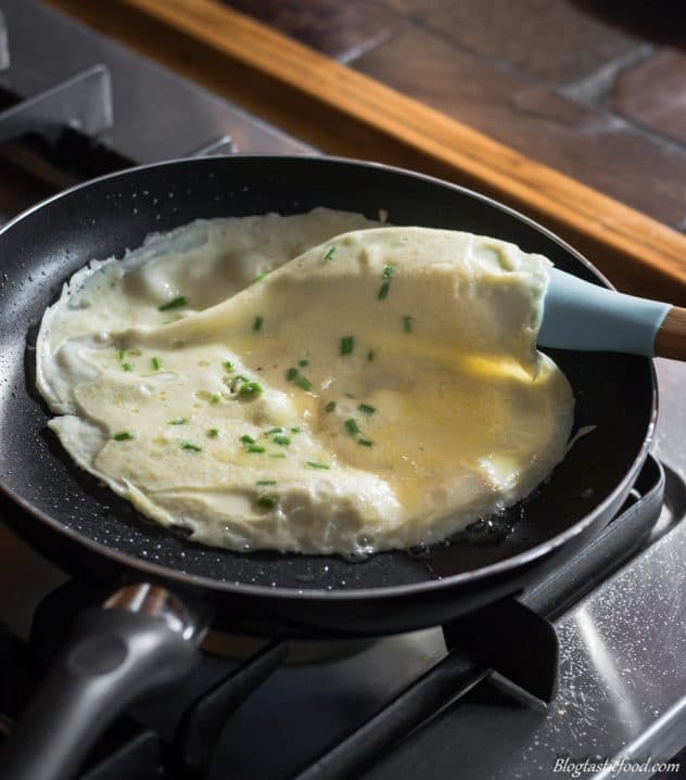 A photo of a half cooked crepe that is about to be flipped in a non-stick pan.