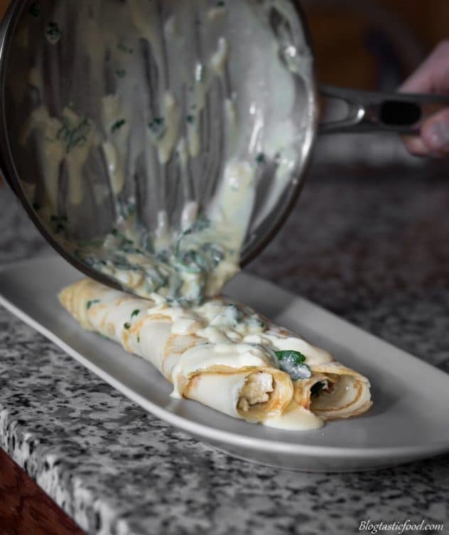Spinach and ricotta filled crepes being topped with lemon butter sauce.