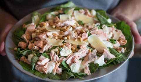 Flaked salmon salad topped with shaved Parmesan served on a plate.