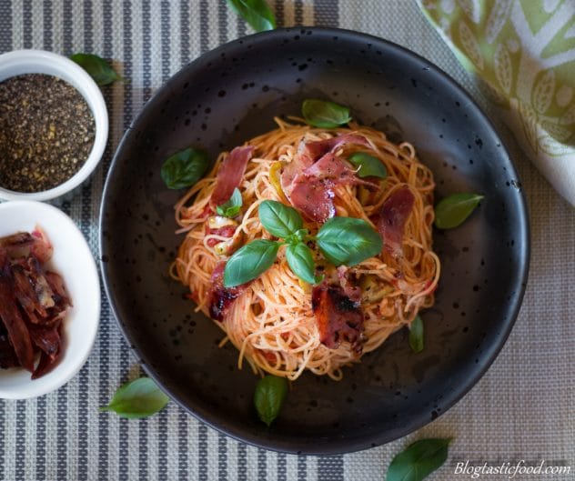 An overhead photo of angel hair pasta with crispy prosciutto in a bowl. 