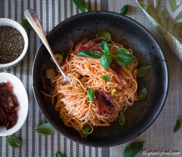 A photo of angel hair napolitana pasta twirled up with a fork. 