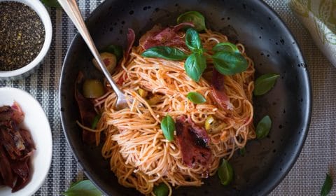 A fork twirling up angel hair pasta in a bowl.