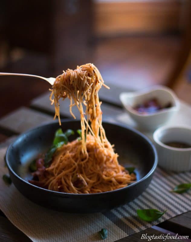  angel hair napolitana pasta in a bowl getting picked up with a fork. 