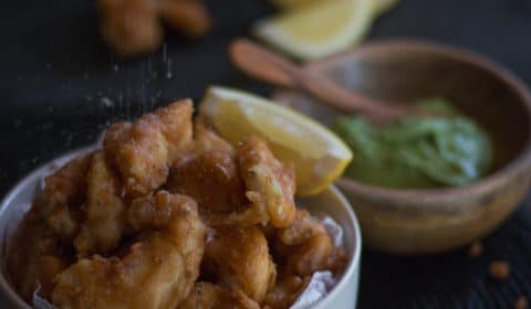A photo of beer battered fish fingers with salt being sprinkled over the top.