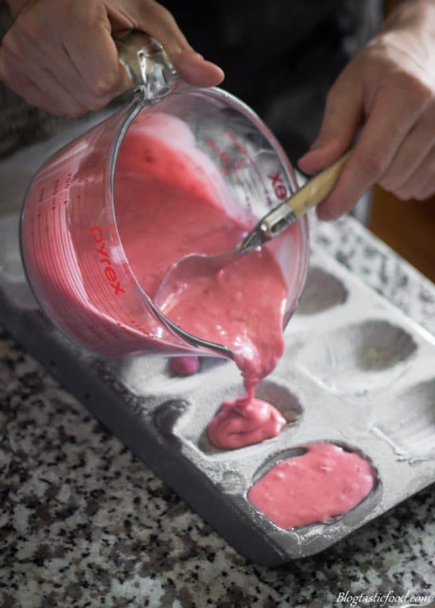 A photo of strawberry Madeleine batter being poured into Madeleine moulds.