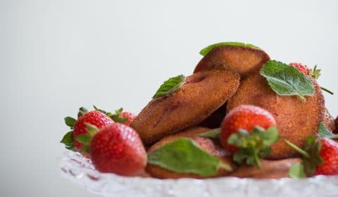 Fresh strawberries and strawberry madeleines served on a cake stand.