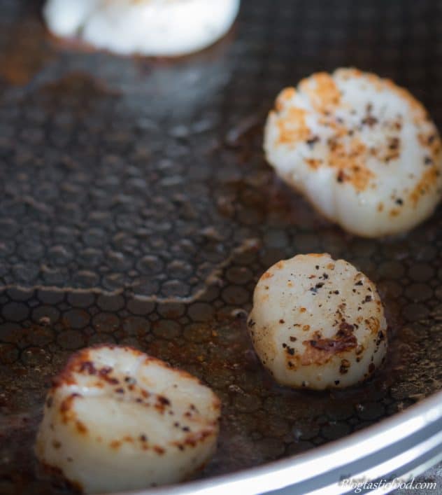 Scallops being seared off in a pan with a nice golden brown colour on them. 