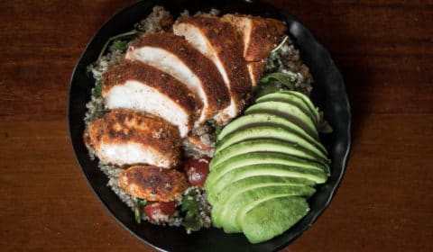 An overhead photo of quinoa salad topped with Cajun chicken and avocado.