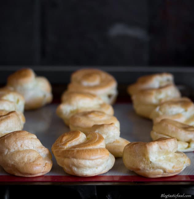 Choux buns on a baking tray that have just come out of the oven. 