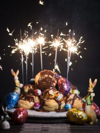 A mountain of chocolate profiteroles with sparkled lighting up on top.