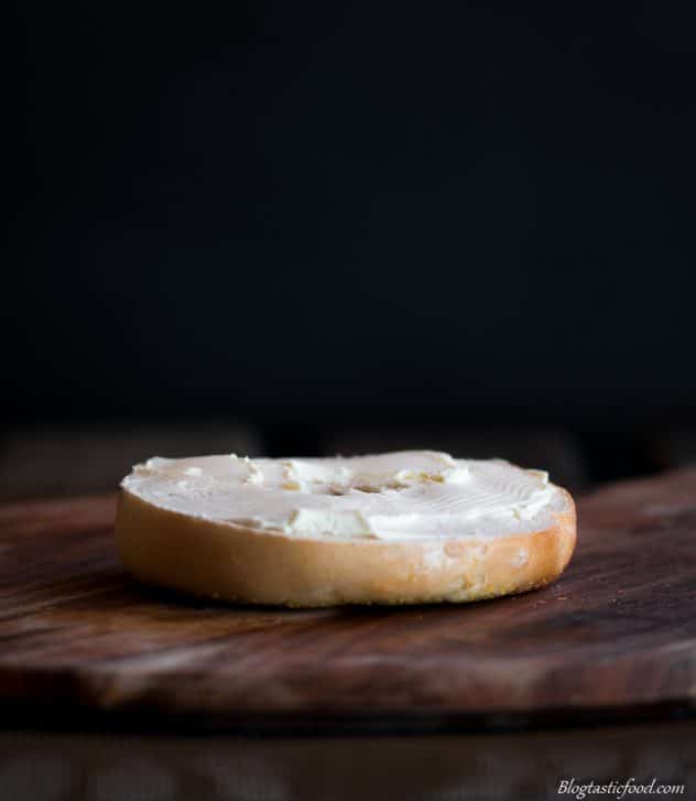 A picture of half a bagel bun with cream cheese spread onto it. 