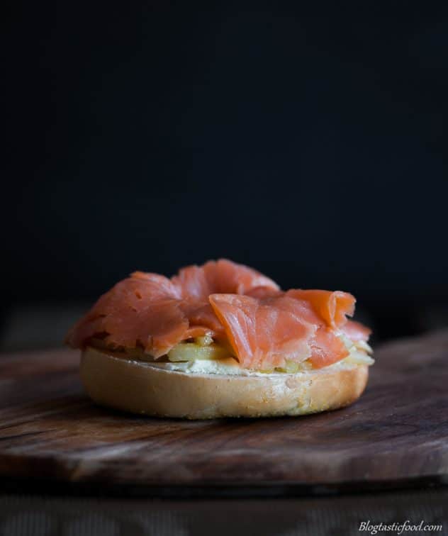 Cream cheese, pan fried fennel slices and smoked trout on half of a bagel bun. 