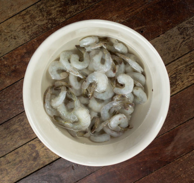 a photo of frozen prawns defrosting in a bowl of water. 