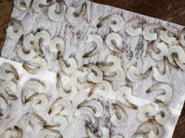 wet, raw prawns drying on kitchen paper. 
