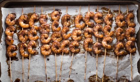 an overhead photo of prawn skewers on a sheet of baking paper.