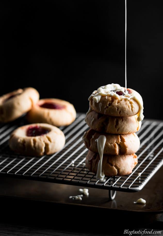 4 peanut butter and jam cookies with white chocolate being drizzled on top.