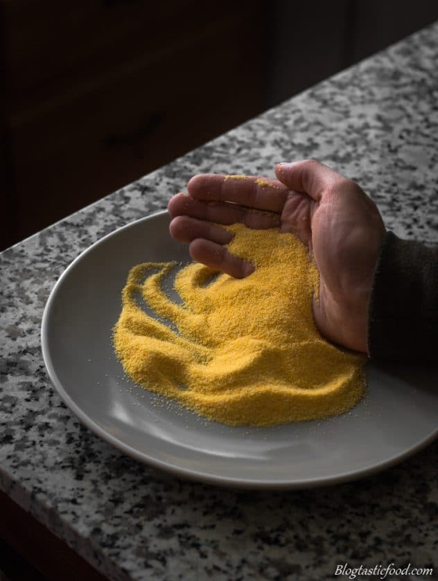 Someone picking up some polenta off of a plate with there hands.