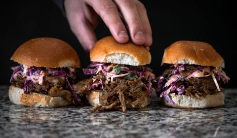 3 pulled pork sliders on a kitchen table.