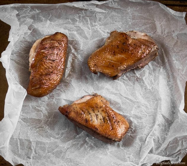 An over head photo of pan-seared duck breast on a sheet of baking paper.