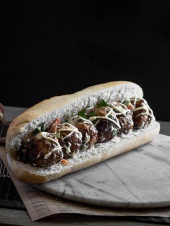A photo of an Asian meatball sub in a marble surface.