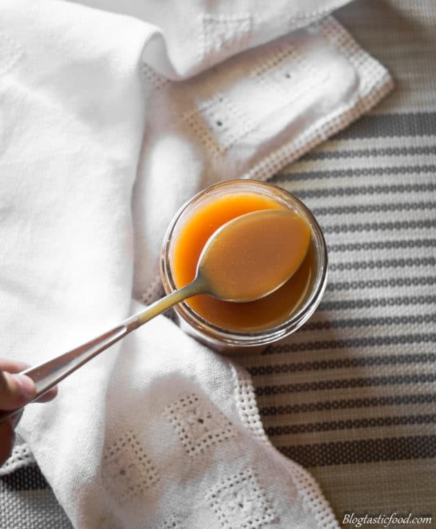 an overhead photo of a spoon lifting some salted caramel out of a jar.