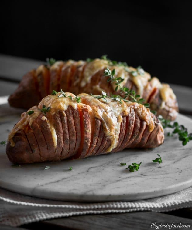 A hasselback sweet potato that has been garnished with fresh thyme. 