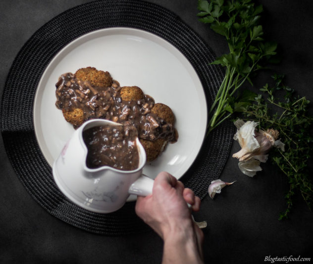 An overheat photo of mushroom gravy being poured over fish fillets.