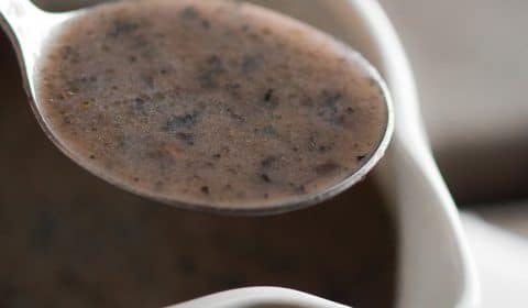 A close up photo of mushroom gravy in a spoon.