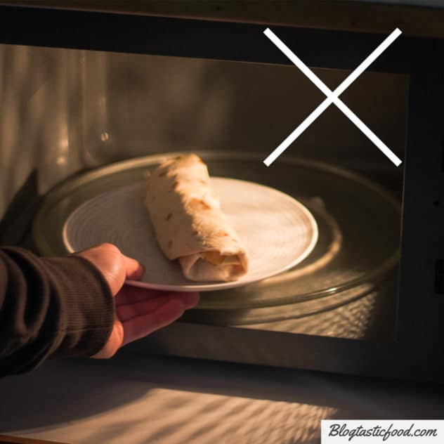 A photo of a frozen burrito on a plate, going in a microwave to defrost. 
