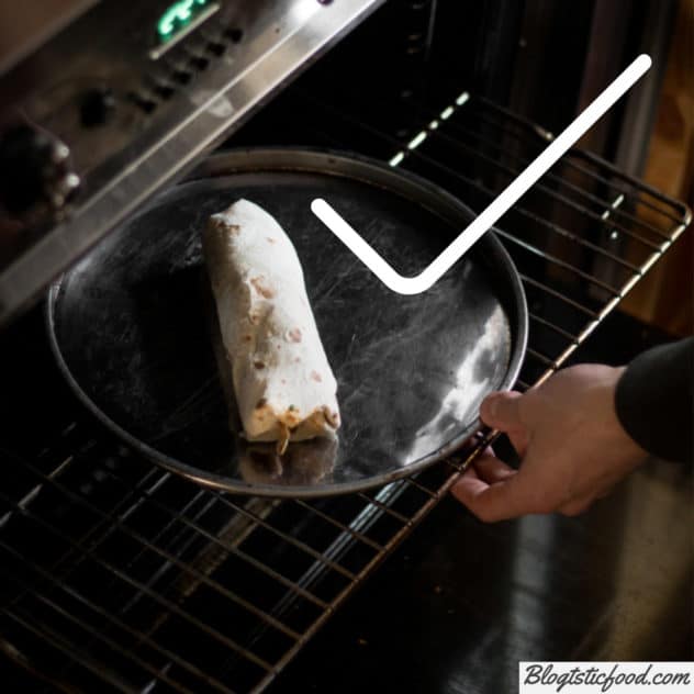 A frozen burrito on a metal tray, going in an oven to defrost. 