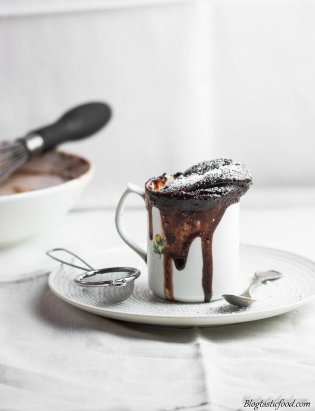 A photo of lava cake in a mug on a plate.